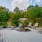 a deck with chairs and tables on it with trees and a fence in the background